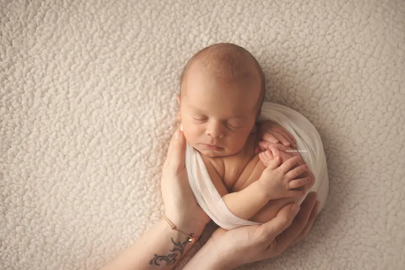 newborn portrait in Orléans, France: tender moment with baby, harmonious wide shot, natural tones