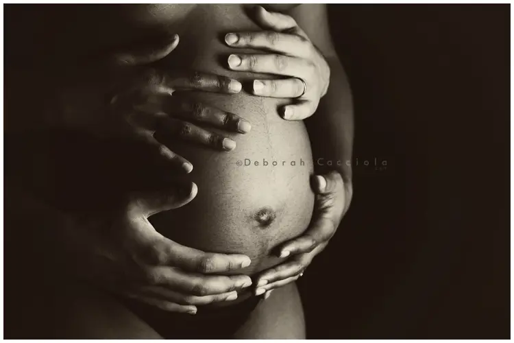foto de embarazo en Orléans, Francia: silueta de maternidad, manos sobre el vientre, paleta suave
