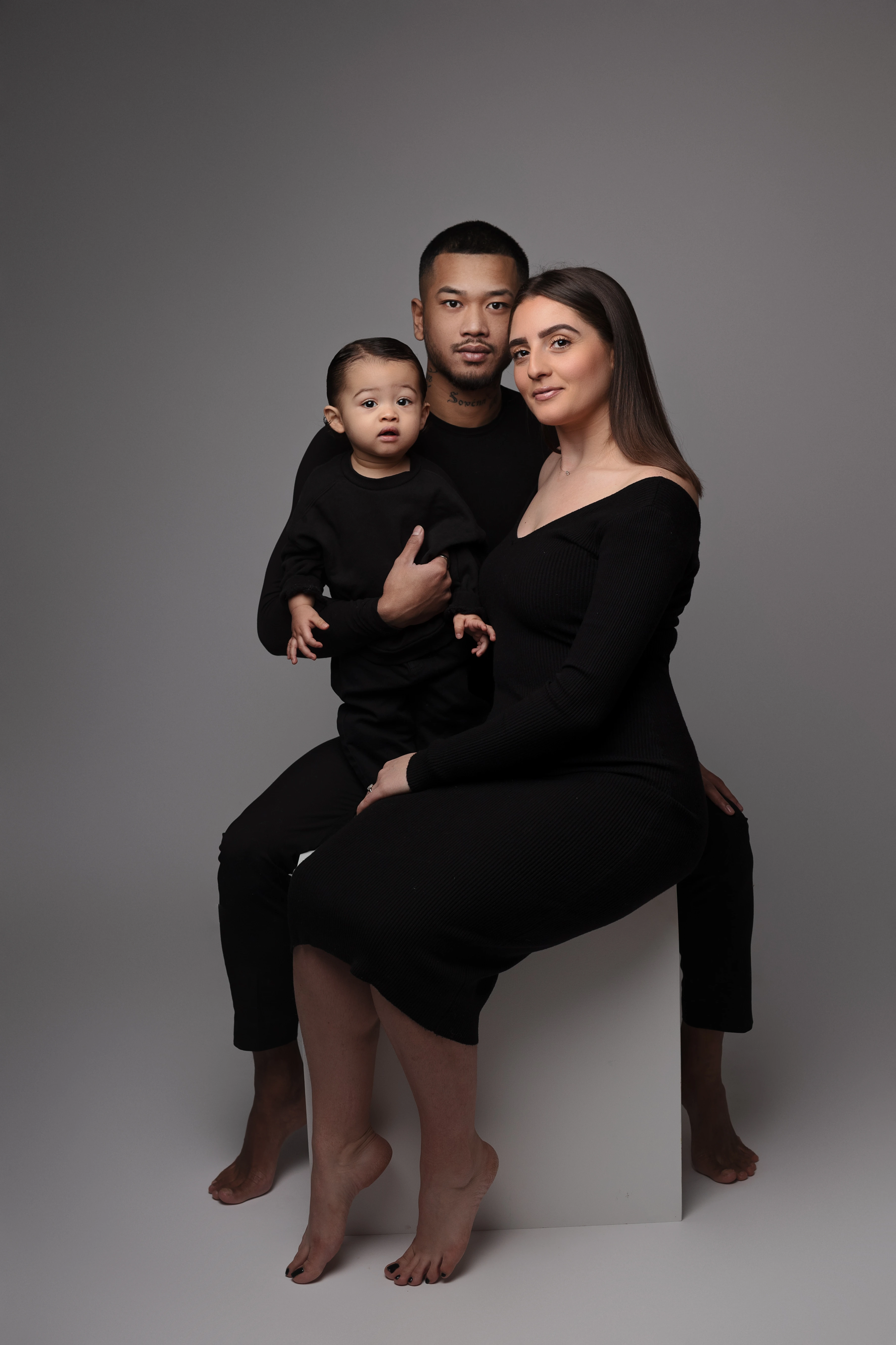 sesión familiar en estudio en Orléans, Francia: familia reunida, encuadre vertical suave, tratamiento cuidado en blanco y negro