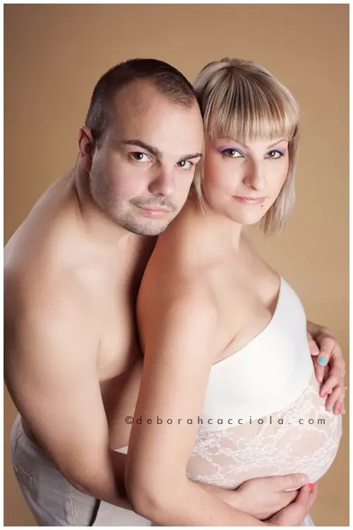 Photo grossesse à Orléans : couple complice, portrait vertical soigné, tonalités naturelles