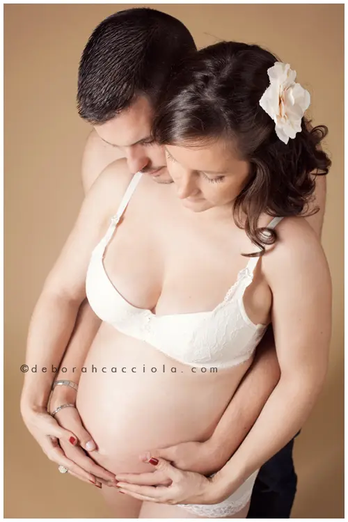 Photo grossesse en studio à Orléans : futurs parents complices, cadrage vertical doux, couleurs naturelles