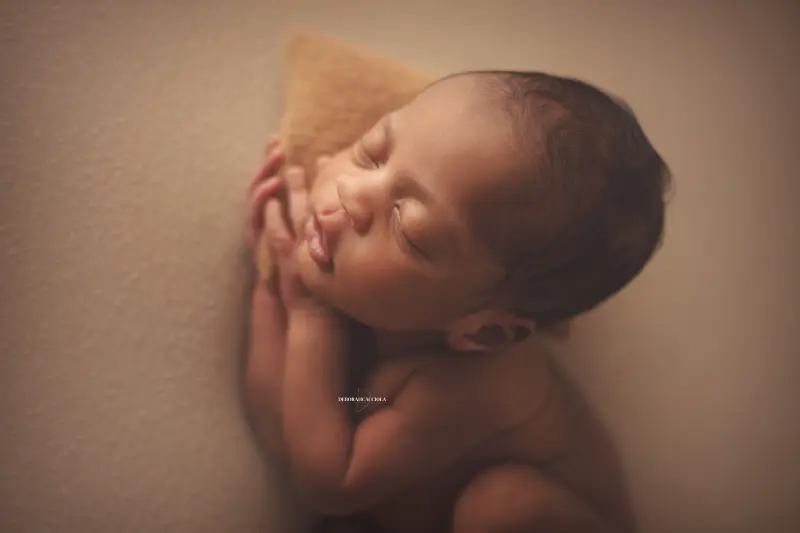 Photo nouveau-né studio Orléans : portrait délicat de bébé, cadrage horizontal équilibré, couleurs douces