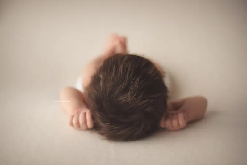 Photo nouveau-né studio Orléans : portrait délicat de bébé, cadrage horizontal équilibré, palette claire