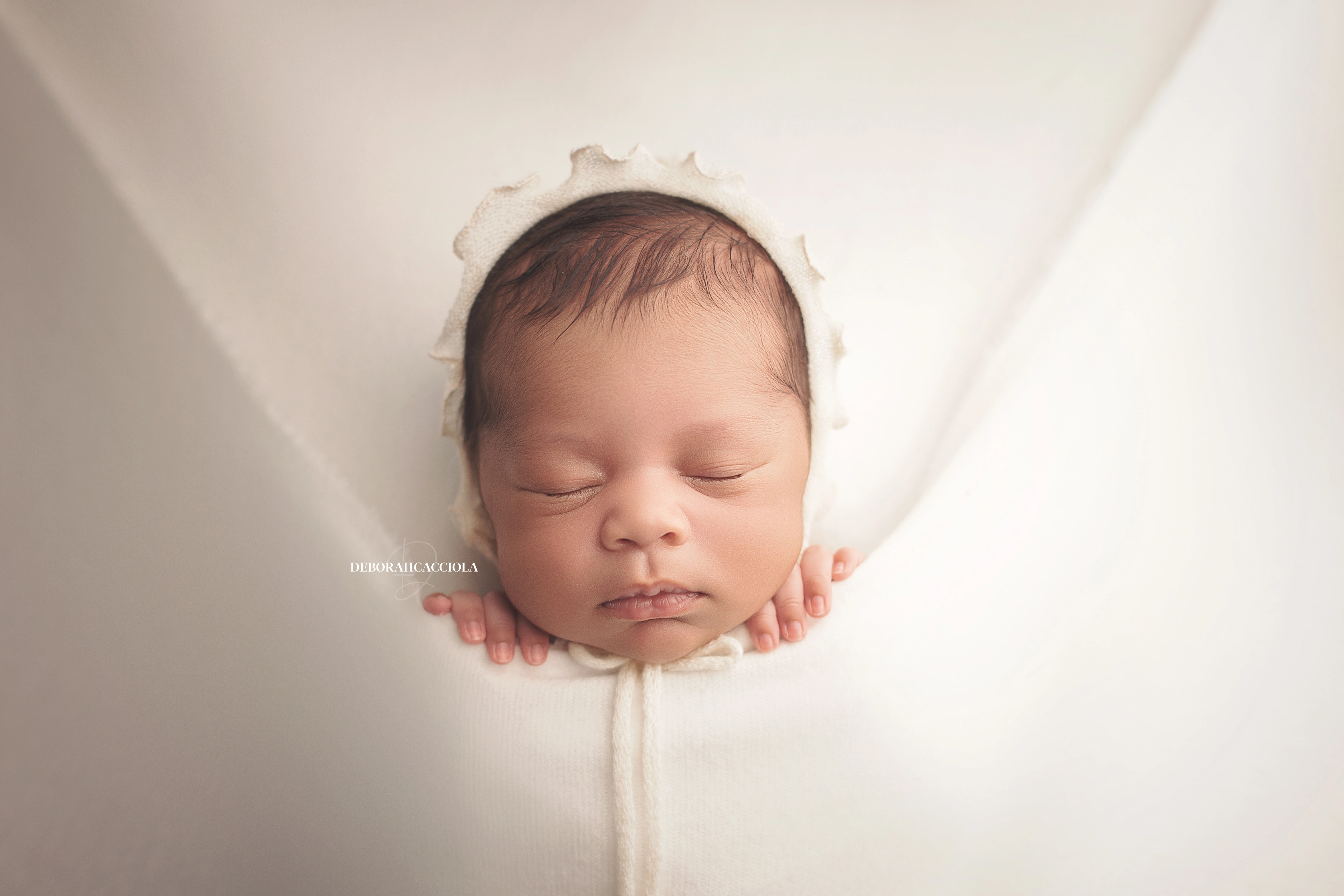 Photo nouveau-né studio Orléans : portrait délicat de bébé, cadrage horizontal équilibré, couleurs douces
