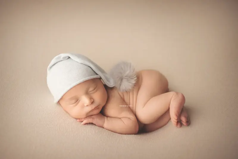 Photo nouveau-né studio Orléans : portrait délicat de bébé, cadrage horizontal équilibré, couleurs douces