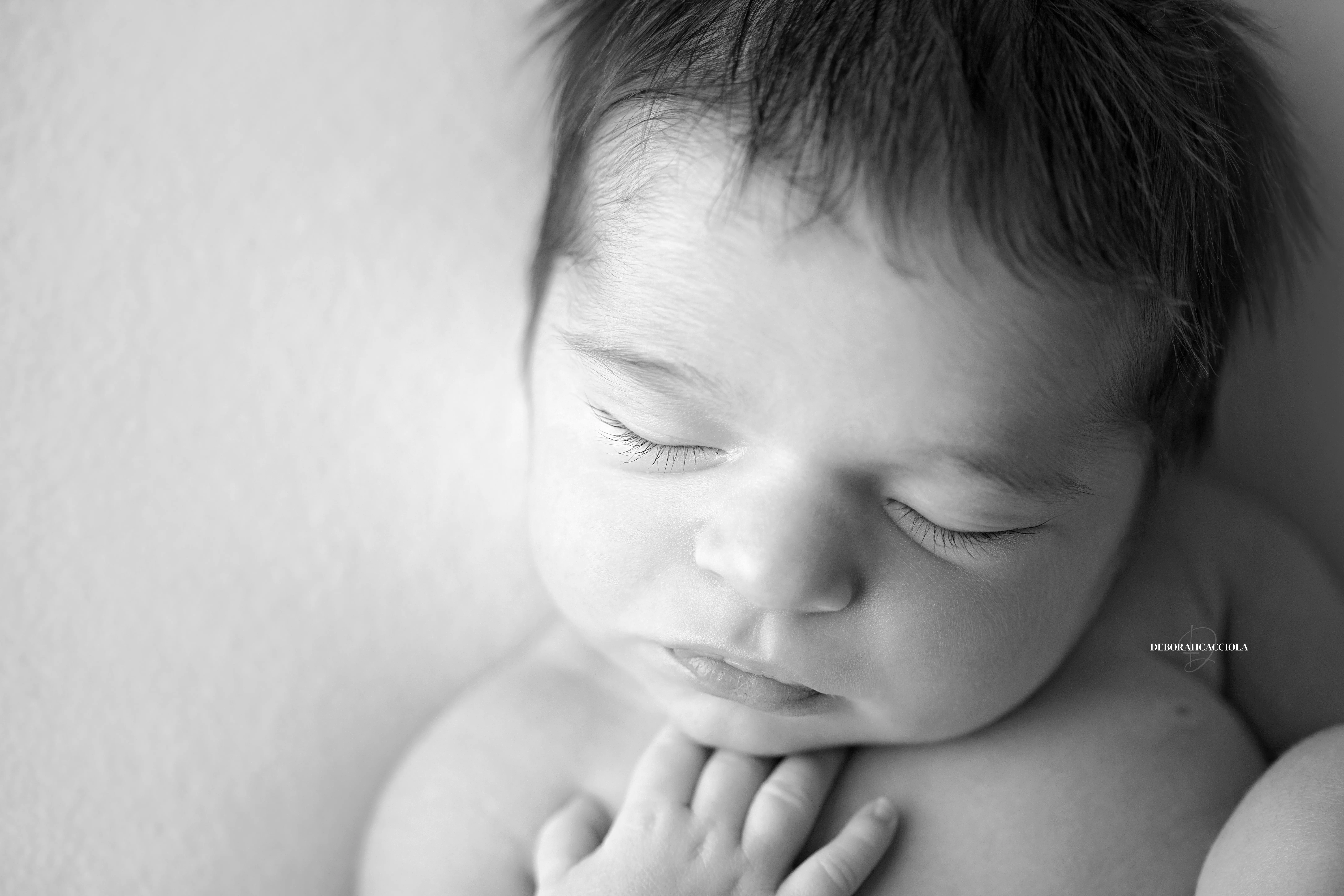 Photo nouveau-né studio Orléans : portrait délicat de bébé, cadrage horizontal équilibré, rendu monochrome