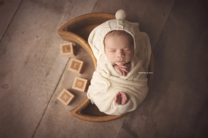 Photo nouveau-né studio Orléans : portrait délicat de bébé, cadrage horizontal équilibré, couleurs douces